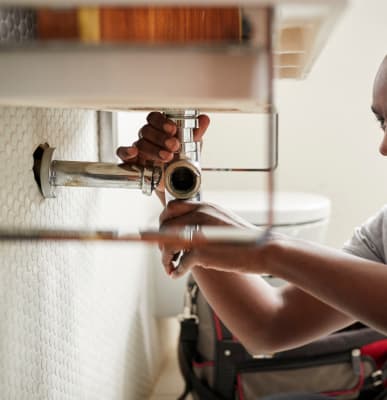 Plumber repairing a pipe under a bathroom sink