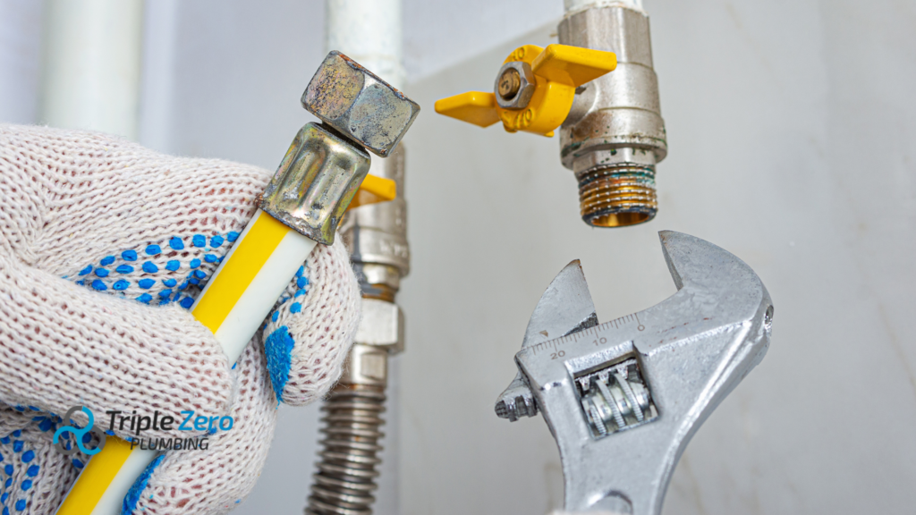 Plumber connecting a yellow gas hose to a valve with a wrench